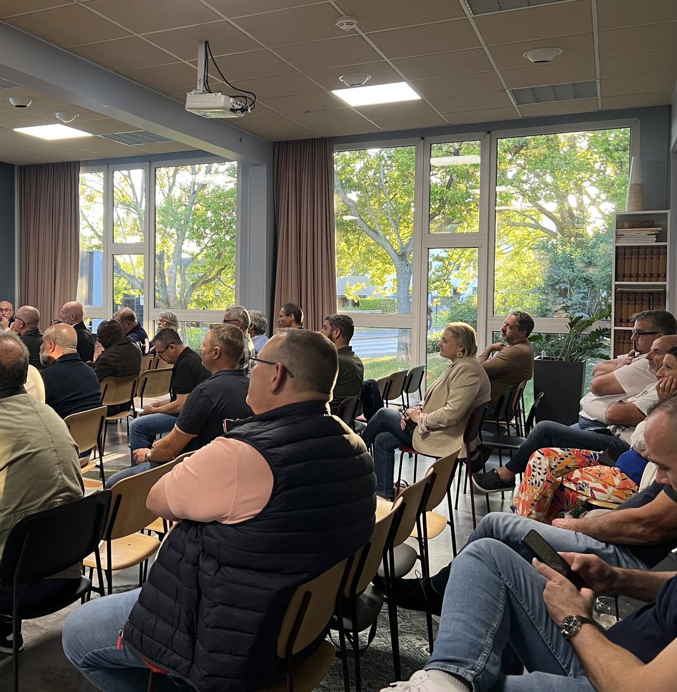 Des adhérents de la FNMS réunis dans une salle ouverte sur un jardin, pendant une présentation.